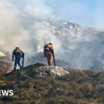 Firefighters assessing a wildfire in Scotland, highlighting the importance of safety during wildfire emergencies.