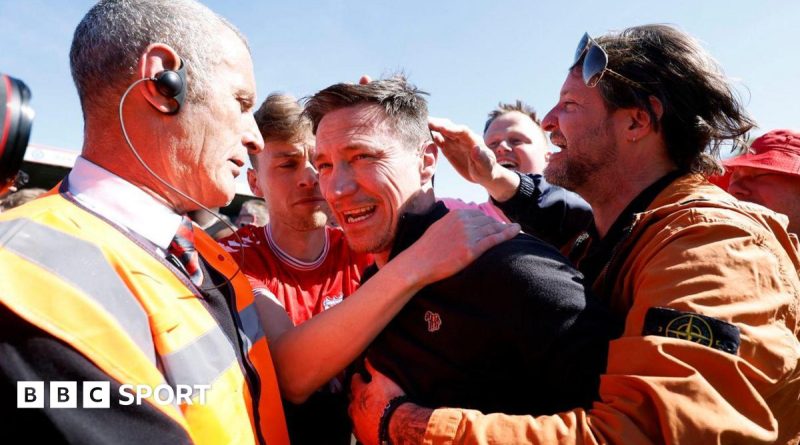 Excited fans celebrating York City promotion at a football stadium.
