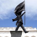 A Banksy statue in London showing a suited man with a flag covering his face.