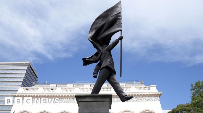 A Banksy statue in London showing a suited man with a flag covering his face.