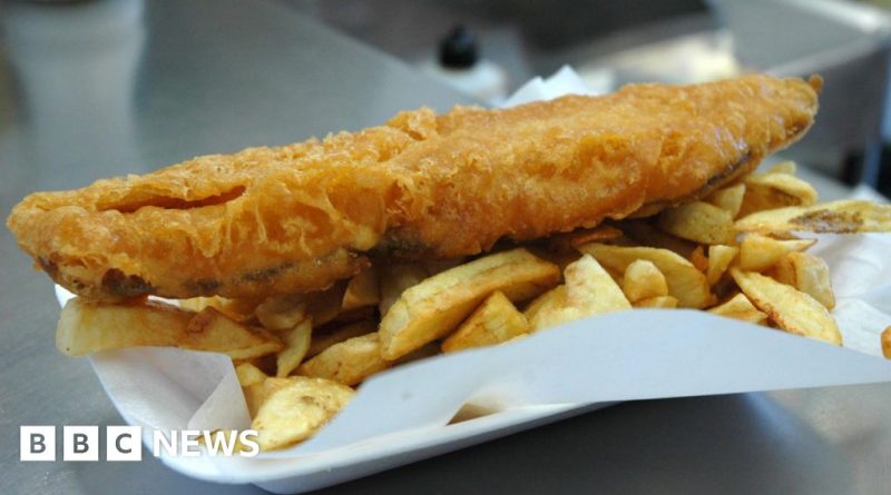 Chefs preparing traditional fish and chips in a busy kitchen setting.