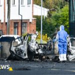Police officers discussing security measures after the Dunmurry police station explosion.