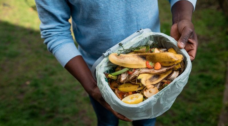 A group of people composting to reduce food waste in a community garden.