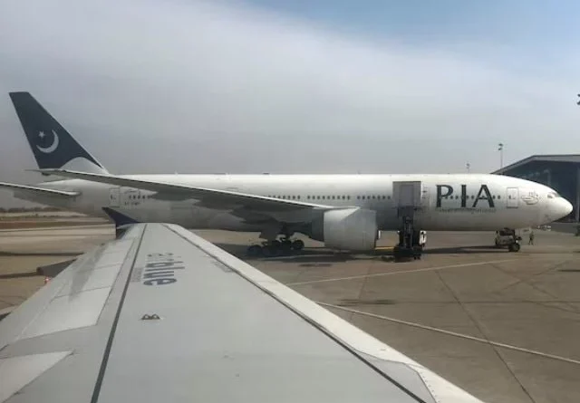Professionals in conservative attire discuss the PIA sale at the airport.