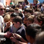 Schoolchildren welcome King Charles in Bermuda with flags and music.