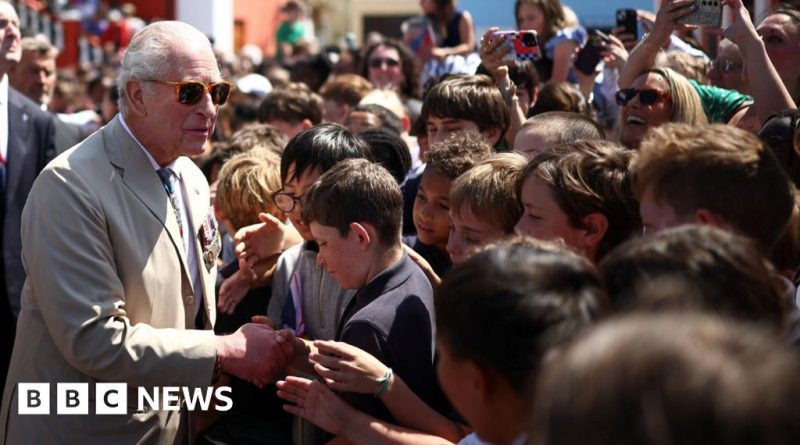 Schoolchildren welcome King Charles in Bermuda with flags and music.