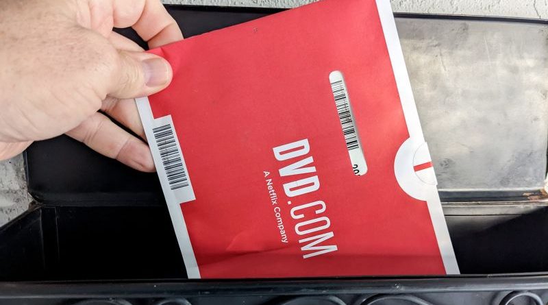 Professionals discuss Netflix DVD service shutdown in modern office.