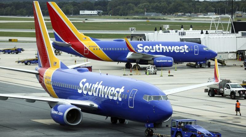 A busy airport terminal scene showing travelers in professional attire during Southwest Airlines flight delays.