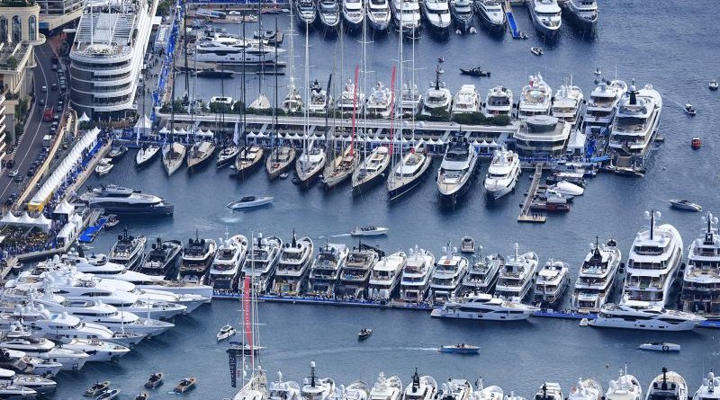 A scene showcasing superyacht sales at a luxury yacht show with elegantly dressed attendees.
