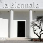 Professionals discussing at the Venice Biennale amid jury resignation news.
